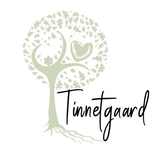 Stiliseret lysegrønt træ med rund krone dannet af små blade og blomster samt et hjerte i kronen, rødder der strækker sig nedad, og foran står teksten "Tinnetgaard" i sort håndskrift.